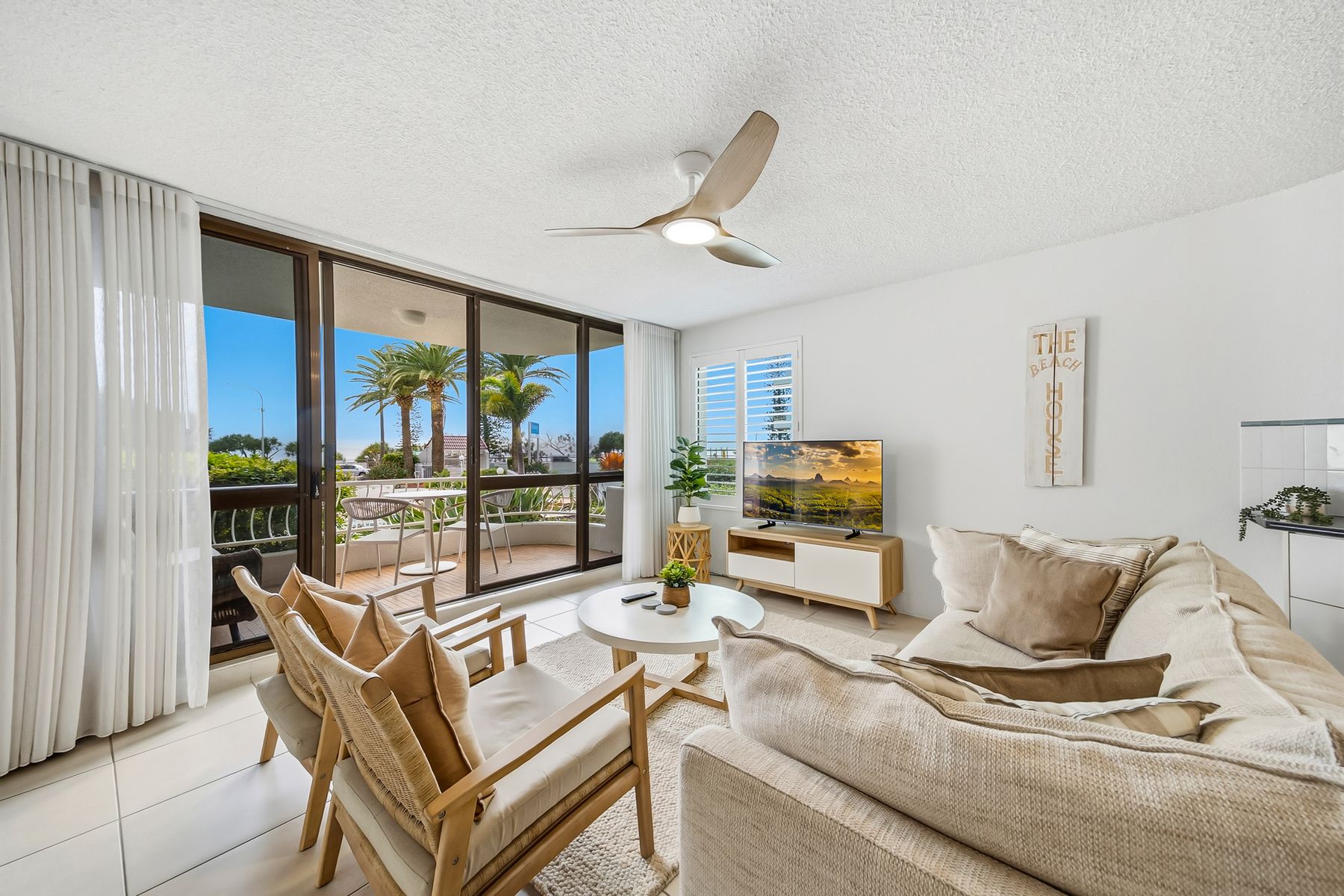 Large fabric lounge in neutral colours is looks out to the balcony and views of the ocean at Unit 7 at Alexandria Apartments