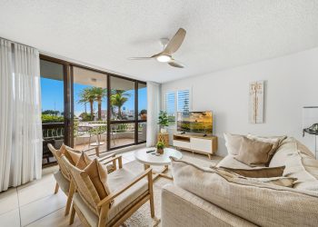Large fabric lounge in neutral colours is looks out to the balcony and views of the ocean at Unit 7 at Alexandria Apartments